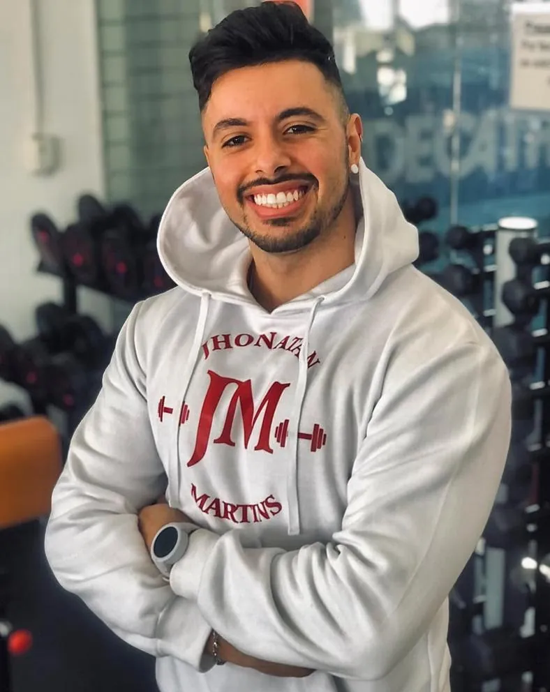 Jhonatan Martins de braços cruzados na academia, com moletom personalizado